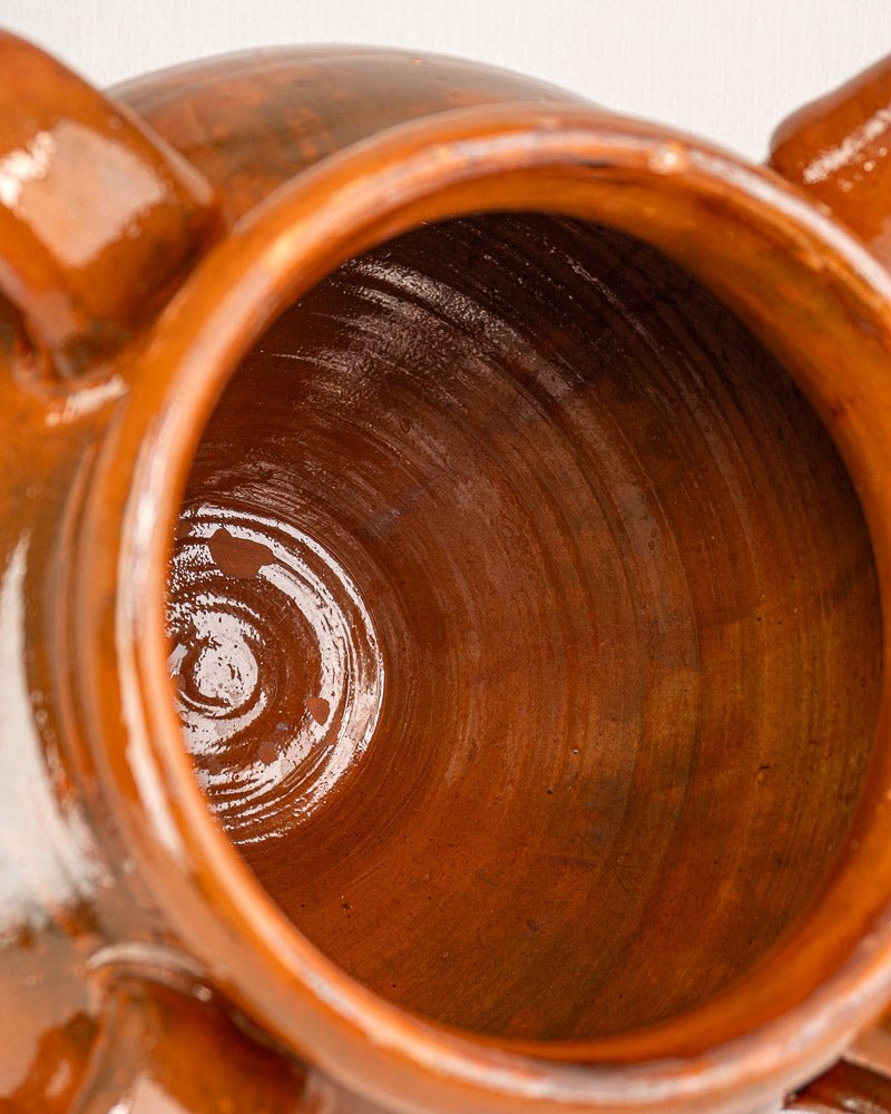 Interior detail of 19th-century French terracotta oil jar with glossy brown glaze and curved lines.