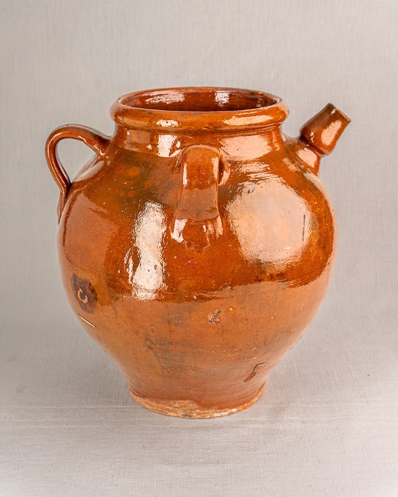 19th-century French terracotta oil jar with brown glaze, handle, and spout on light background.