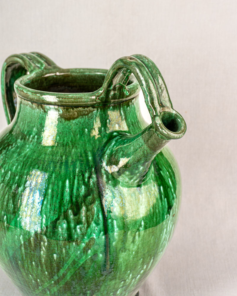 19th-century French green glazed cruche with ribbed texture, two curved handles, and spout on a plain light background.