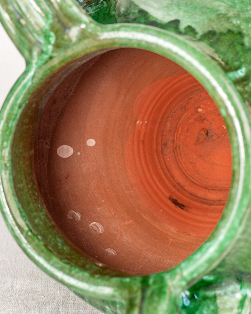 Antique French cruche in green glazed earthenware, reddish-brown interior, partially visible rim, 19th-century.