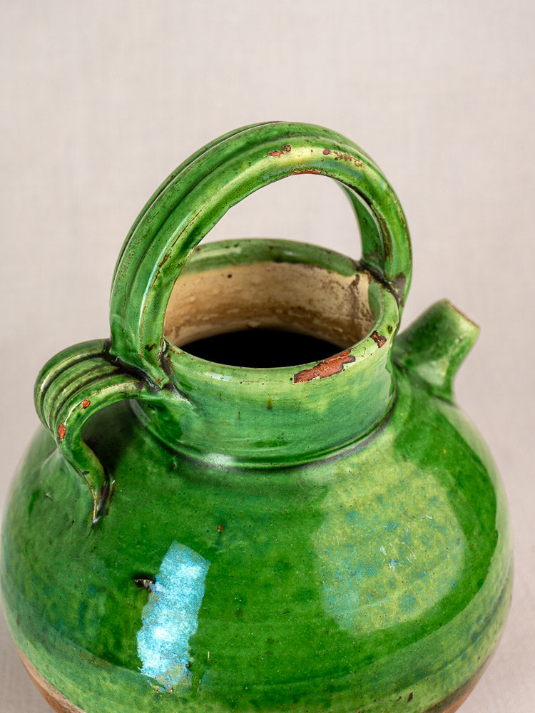 Antique French green glazed terracotta gargoulette with round handle, small spout, and chips on rim and handle.