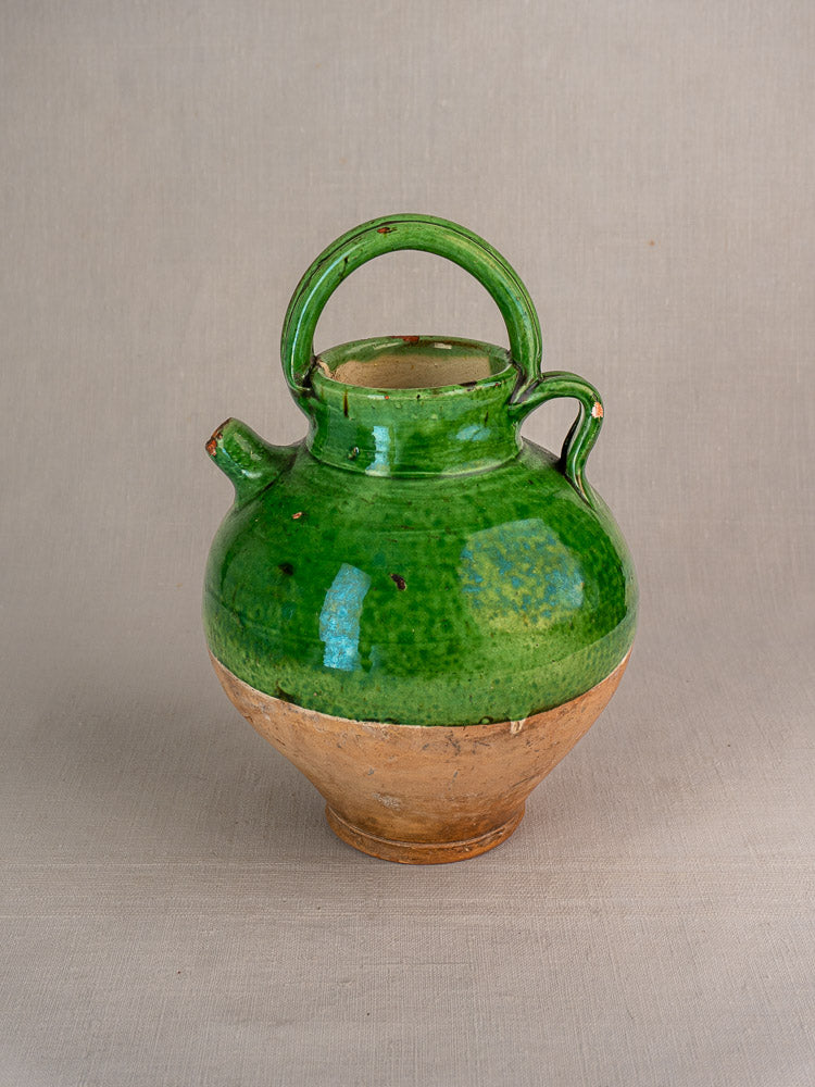 Antique French green glazed terracotta gargoulette cruche with rounded base, unglazed lower half, curved handle, and short spout.