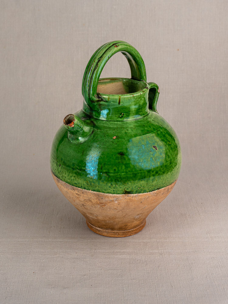 Antique French Provençal gargoulette with green-glazed terracotta top, beige base, handle, and spout on plain background.