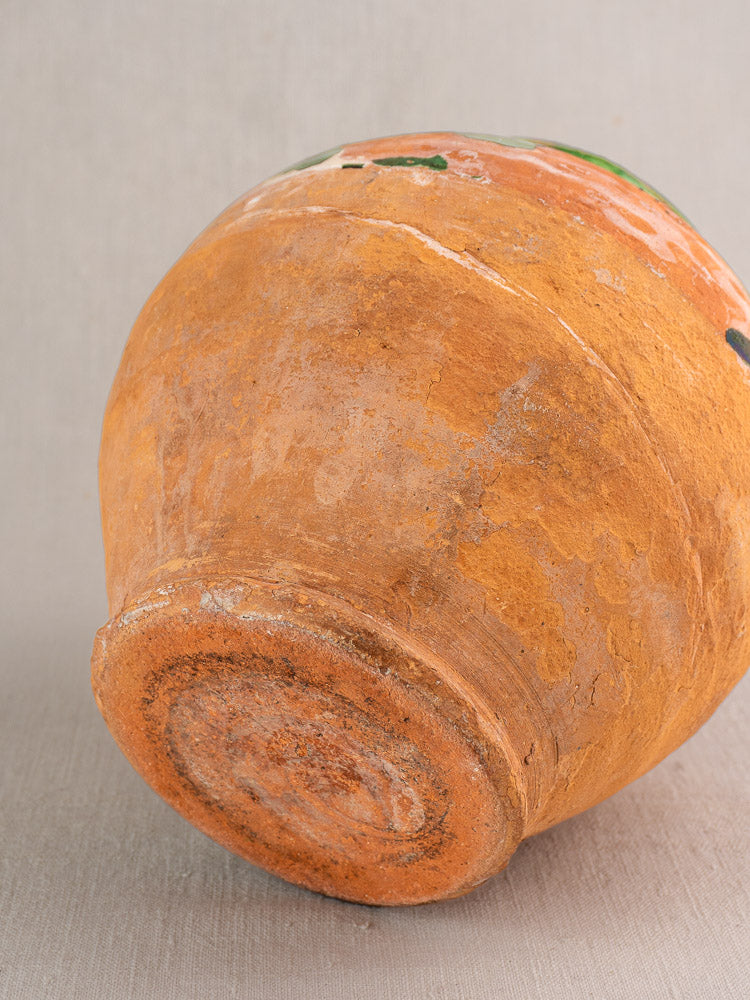 Close-up of antique French green glazed earthenware gargoulette base with aged patina, set on neutral background.