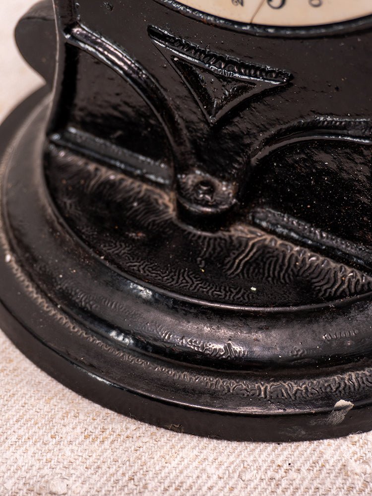 Black textured cast iron base of Antique Salter Kitchen Scale No. 50 on beige fabric surface.