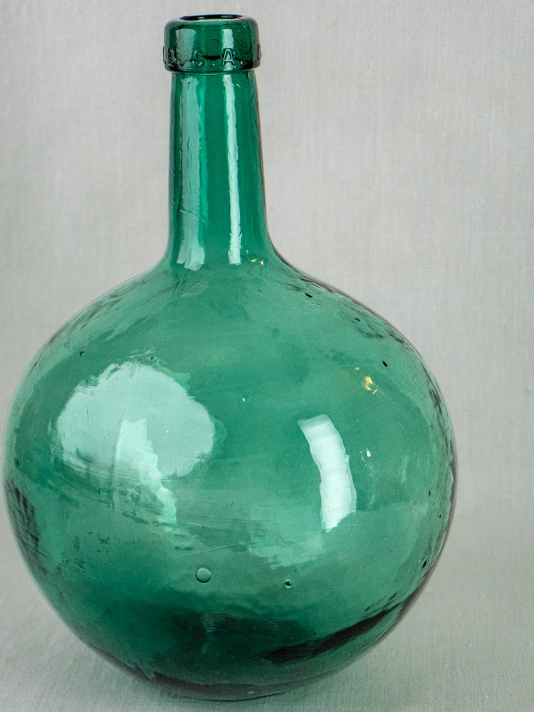 Three antique hand-blown green glass demijohns with round bodies and narrow necks on light gray background.