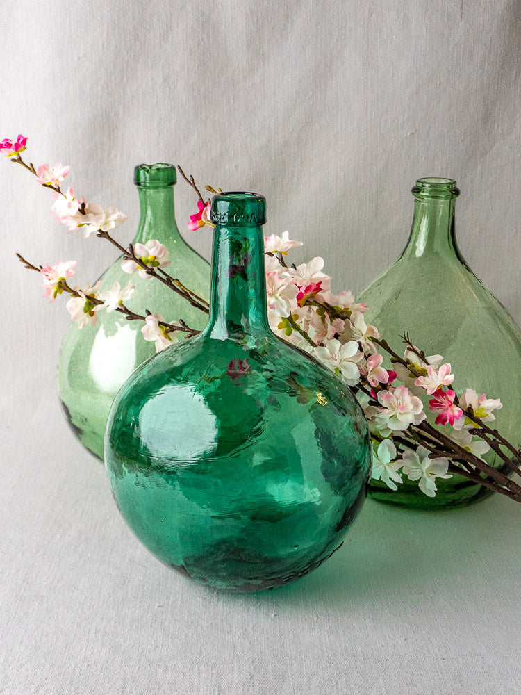 Set of three antique Spanish green glass demijohns with round bases, cherry blossom accents.