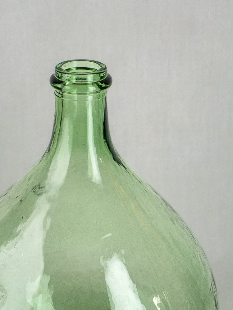 Hand-blown Spanish green glass demijohn with a narrow neck, set against a light gray background.