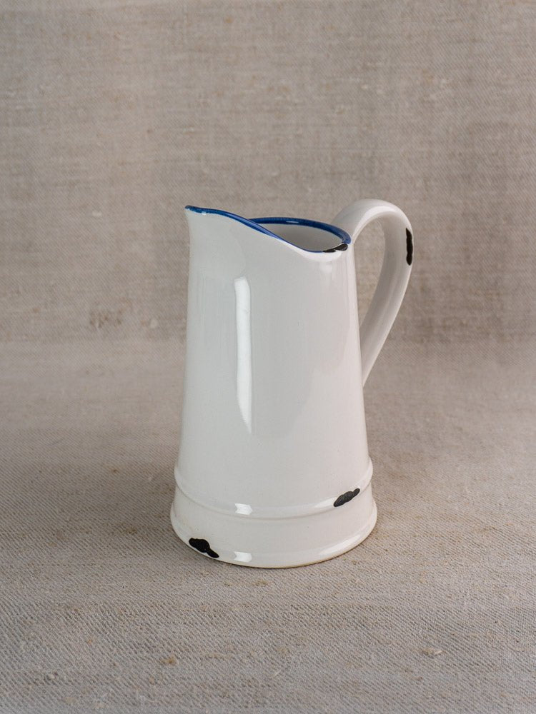 Vintage French faience pitcher in white ceramic with blue-trimmed interior and graceful curved handle.