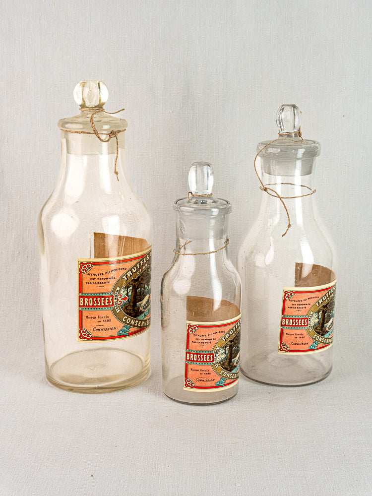 Set of three antique French L. Jaubert truffle jars with orange labels and string ties.