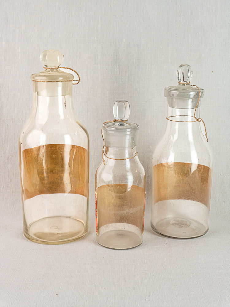 Three antique French L. Jaubert truffle jars with round glass stoppers and aged patina.