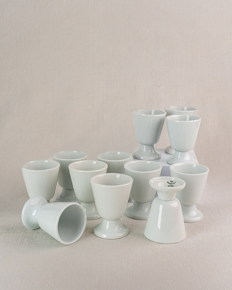 Set of twelve vintage French porcelain Mazagran coffee cups by CNP Tradition France on light fabric.