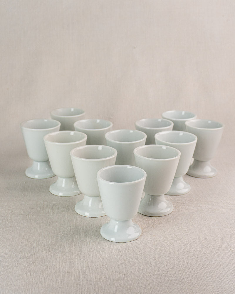 Set of 12 vintage French porcelain Mazagran coffee cups by CNP Tradition, on beige fabric background.