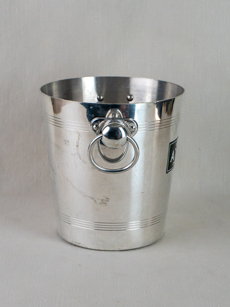 Vintage French Argit aluminum champagne bucket with engraved lines, handle ring, and black label on light surface.