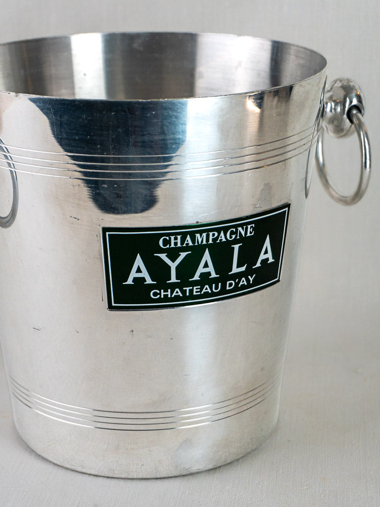 Vintage French Ayala Champagne bucket with side handles and green and white label on front.