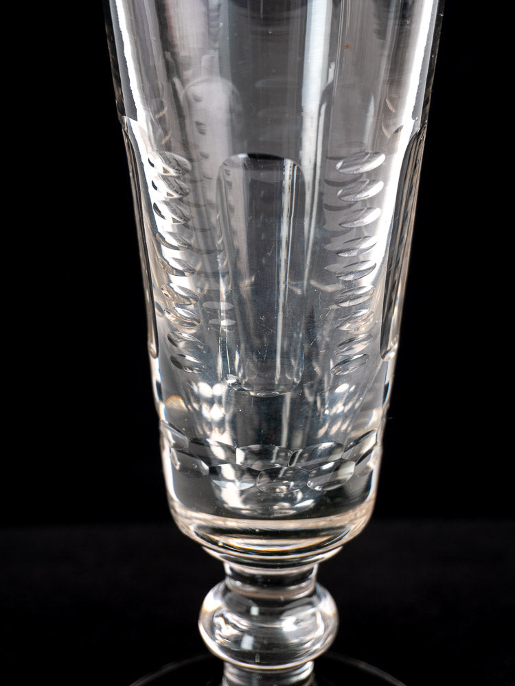 Set of six antique French uranium glass beer flutes, clear and decorative, arranged upright against a black background.