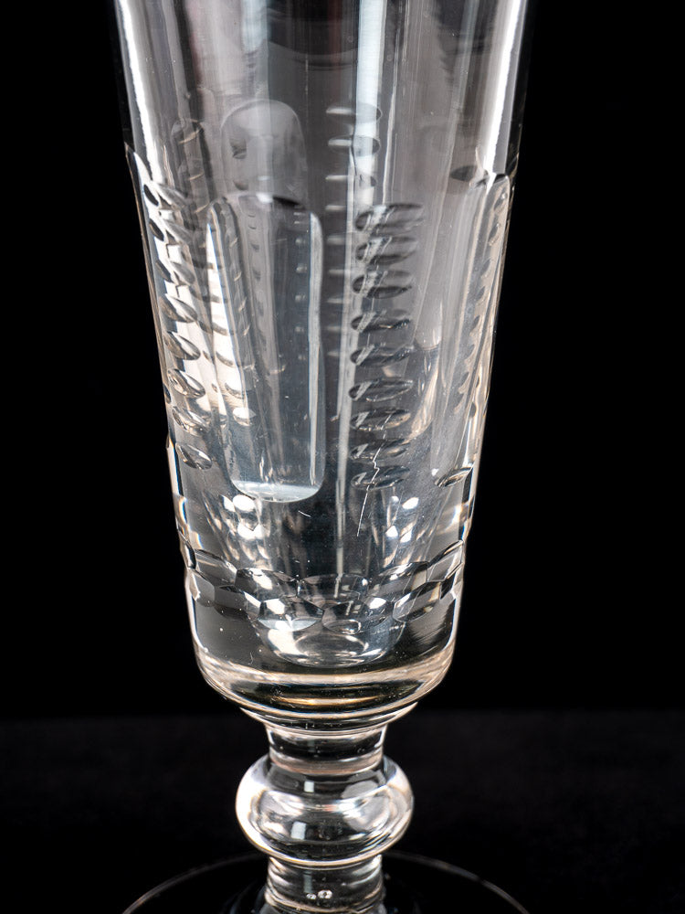 Antique French uranium glass beer flute c.1900 with cut vertical and diagonal patterns, upright on a black background.