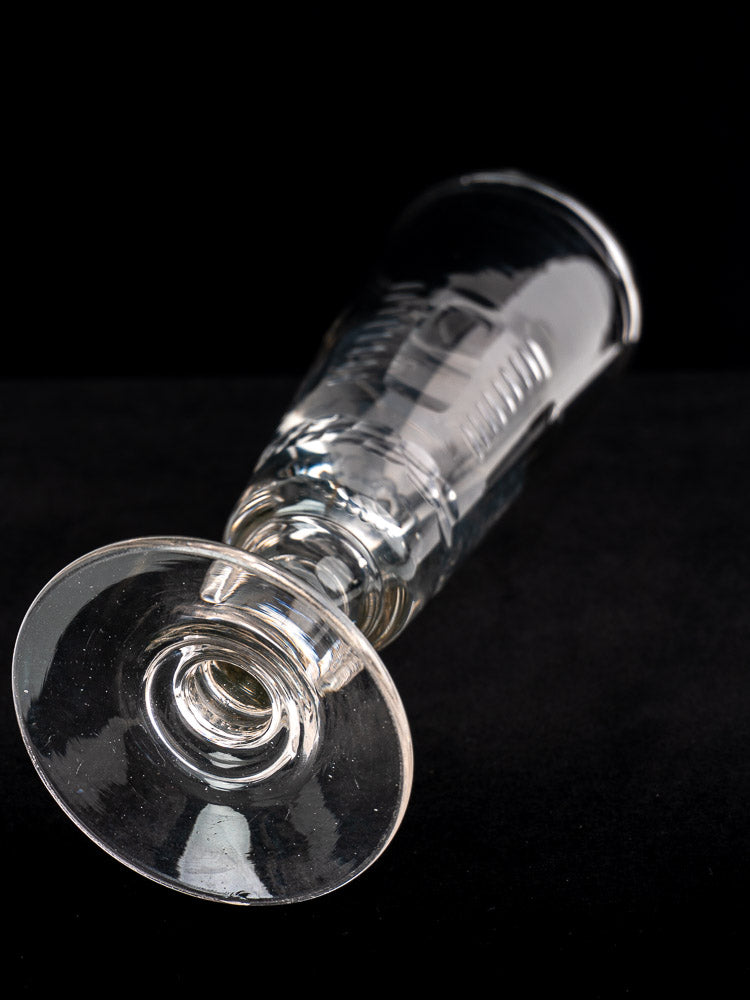 Antique French uranium glass beer flute from c.1900 set, shown on its side against black background.