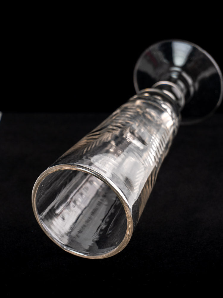 Antique French uranium glass beer flute, c.1900, shown on its side with textured surface and wide rim against black background.
