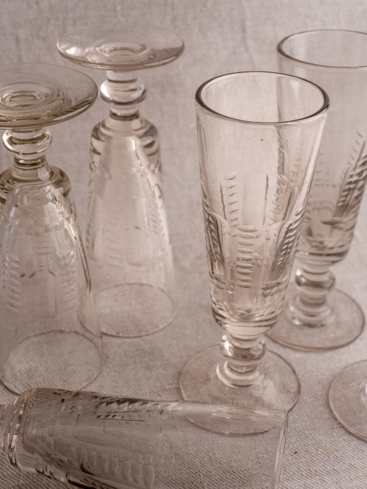 Set of six antique French uranium glass beer flutes, c.1900, displayed on textured fabric.