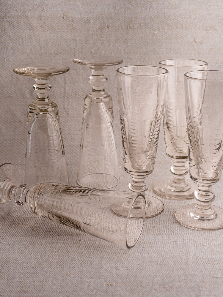 Set of six antique French uranium glass beer flutes, c.1900, arranged on linen with varied positioning.