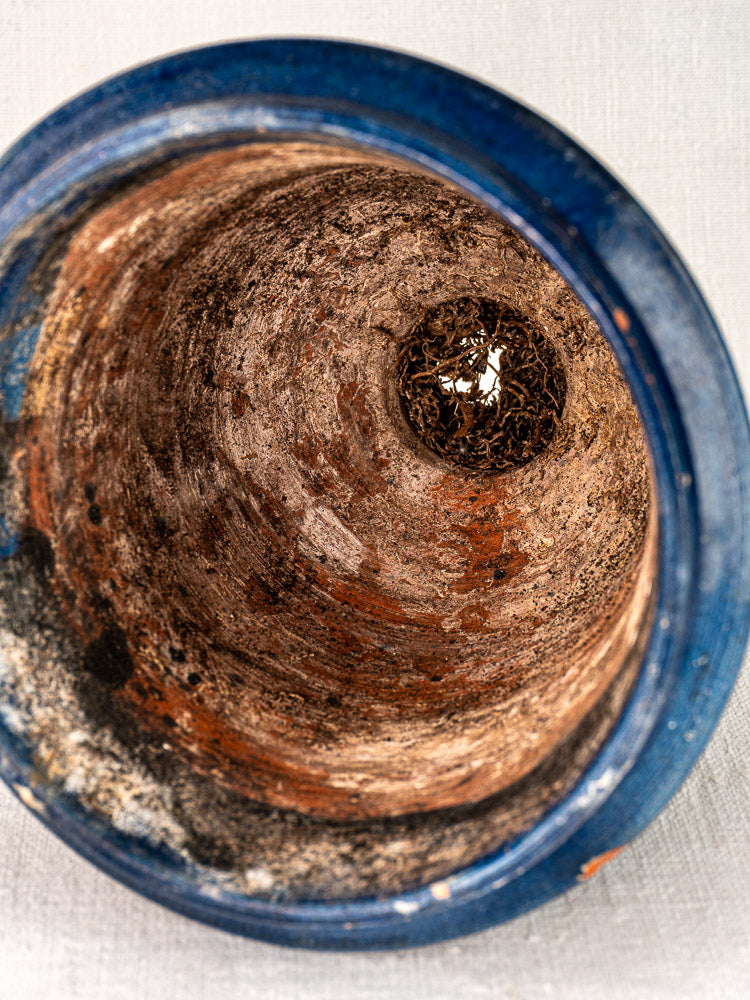Top-down view of antique French blue glazed terracotta Medici vase with worn interior and dried plant matter.