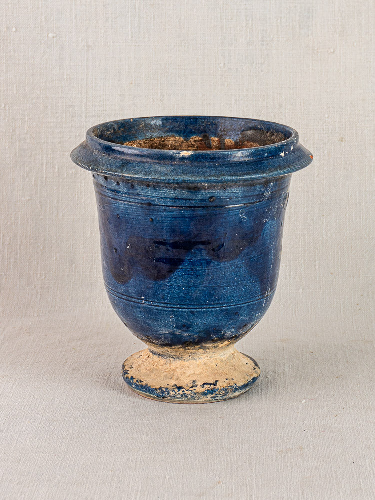 Antique French Medici vase, blue glazed terracotta with wide rim and flared foot, on neutral background.