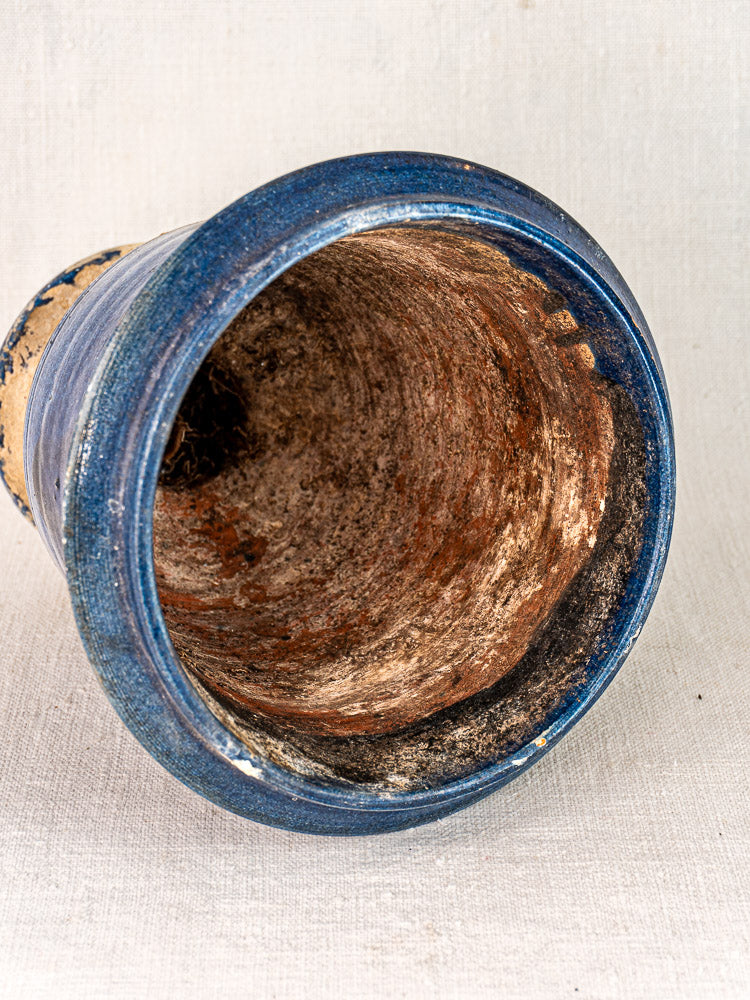 Antique French Medici Vase with blue glazed terracotta, visible inner dirt and mold, on light fabric background.