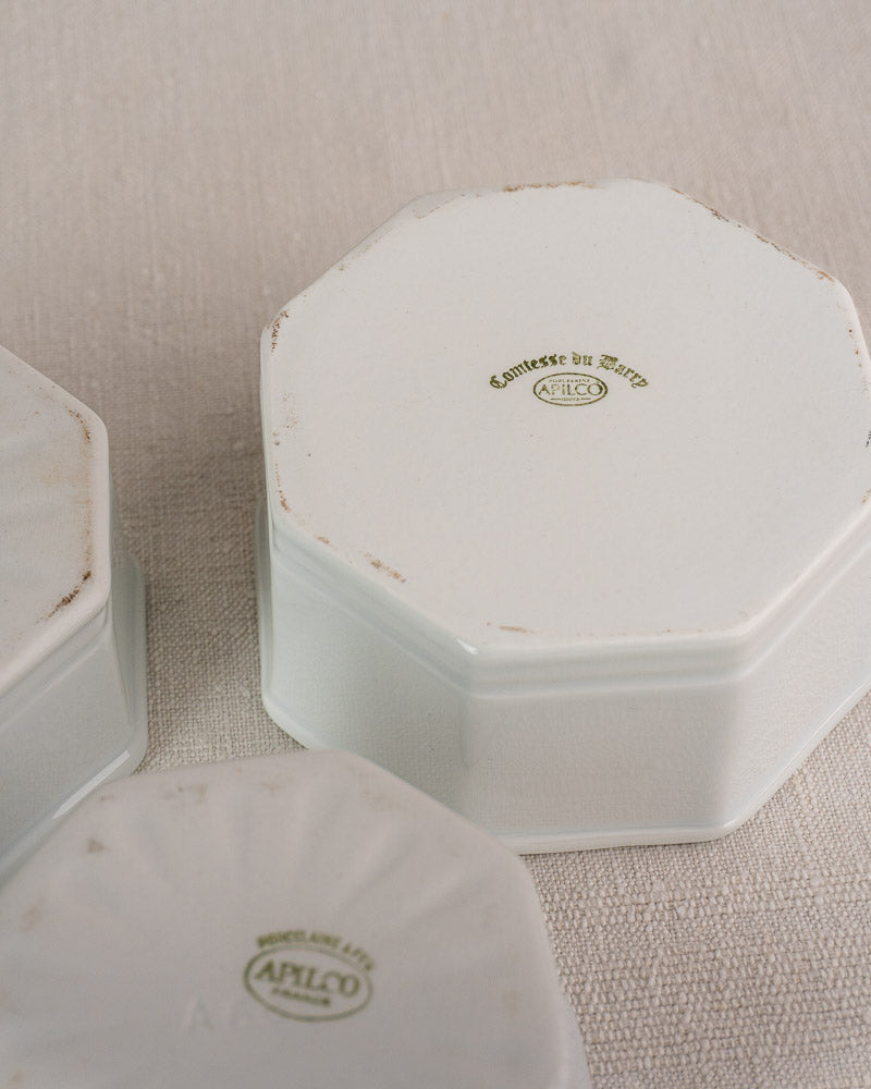 Three white octagonal Apilco porcelain dishes, upside down, showing green maker’s marks and edge wear.