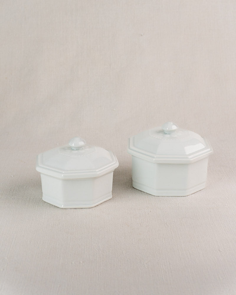 Set of three vintage French Apilco octagonal porcelain pots with lids on a beige surface.