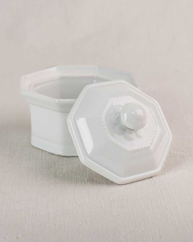 Vintage French Apilco porcelain pot, white and octagonal with matching lid, on light textured surface.