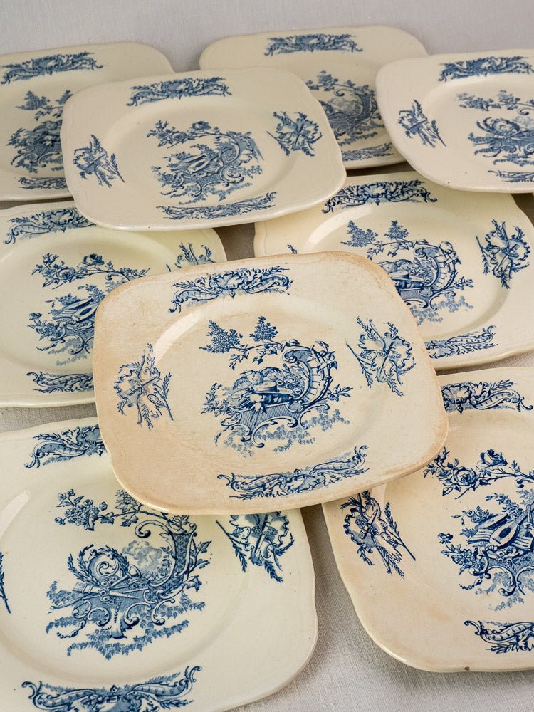 40-piece antique French Clairefontaine faience plates with blue floral designs, arranged overlapping on a light surface.