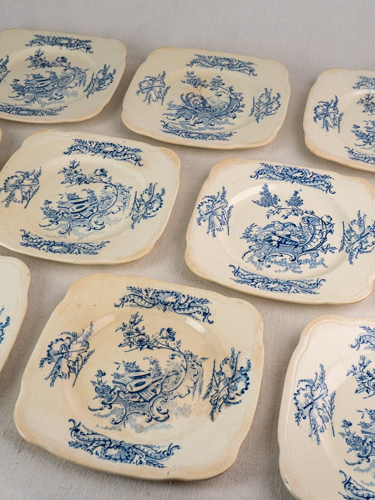 Seven antique French faience plates with blue floral and bird designs, scalloped edges, light wear.