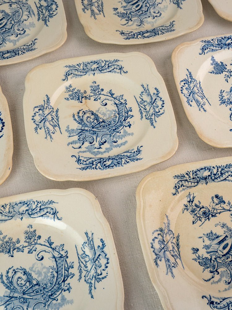 Antique French Clairefontaine faience square plates with blue floral motifs, scalloped edges, and aged patina.
