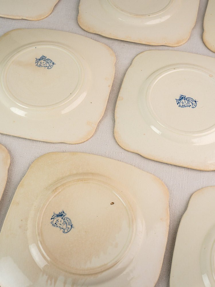 Antique French Clairefontaine Faience plates, cream with scalloped edges, show blue maker’s marks.