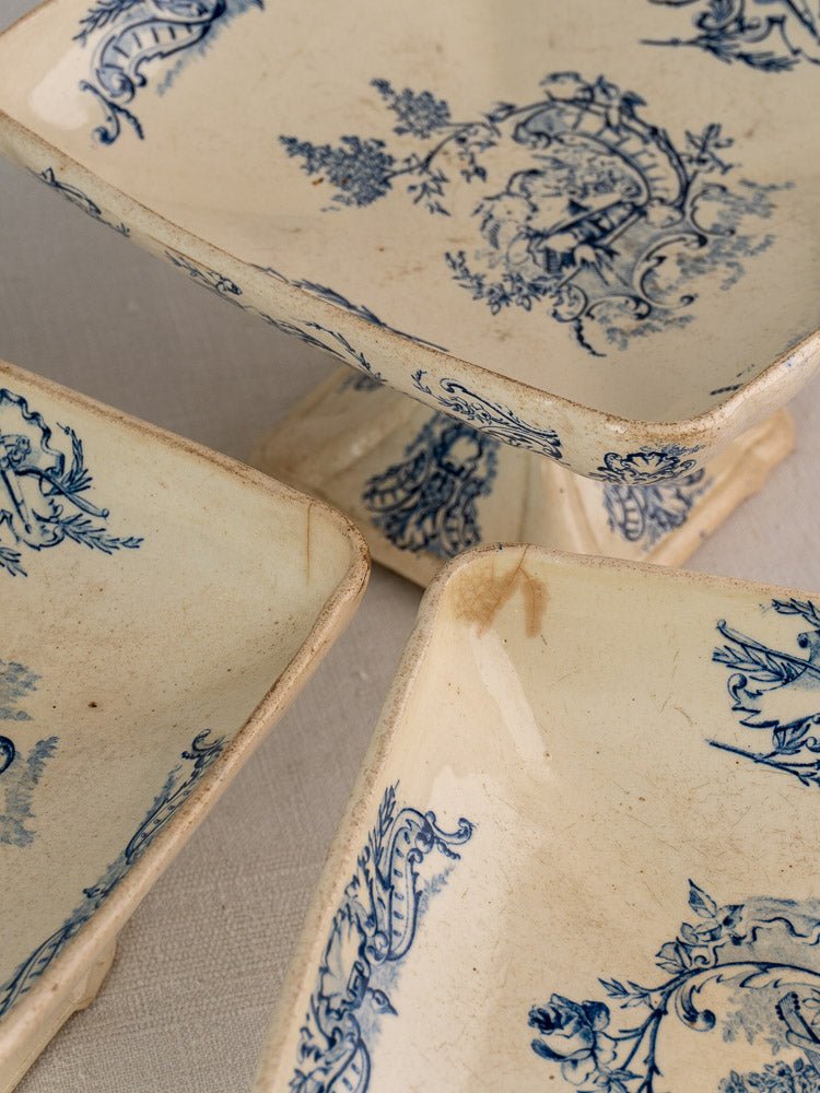 Three antique French Clairefontaine faience pedestal dishes with blue floral patterns and visible age marks.