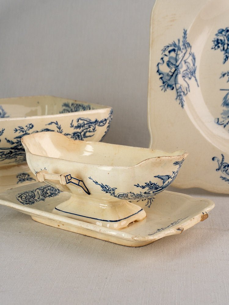 Antique French Clairefontaine faience 40-piece service with cream ceramic and blue floral motifs, set on a neutral background.