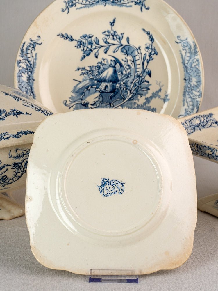 Square cream ceramic plate with blue maker’s mark and round Clairefontaine faience plate with blue floral motifs.