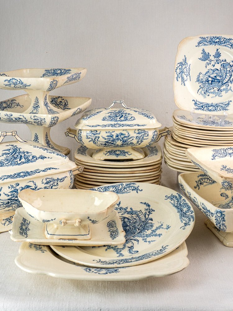 Antique French 40-piece Clairefontaine faience service with blue floral patterns, stacked on a neutral background.