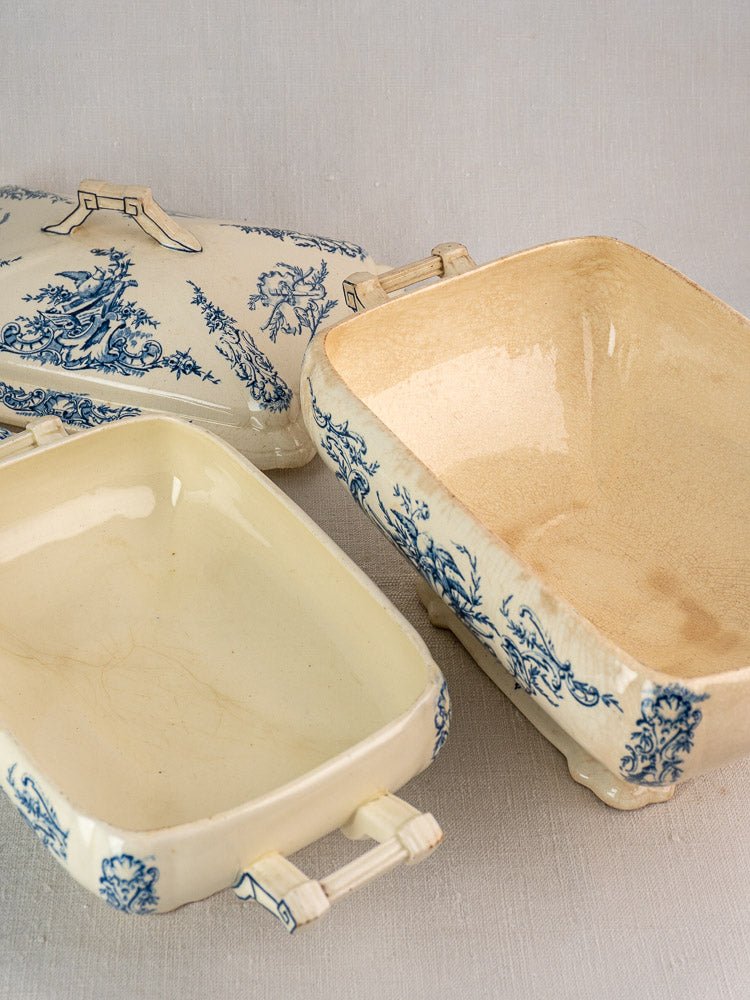 Rectangular Clairefontaine faience dishes with blue floral designs and a lidded piece on a neutral surface.