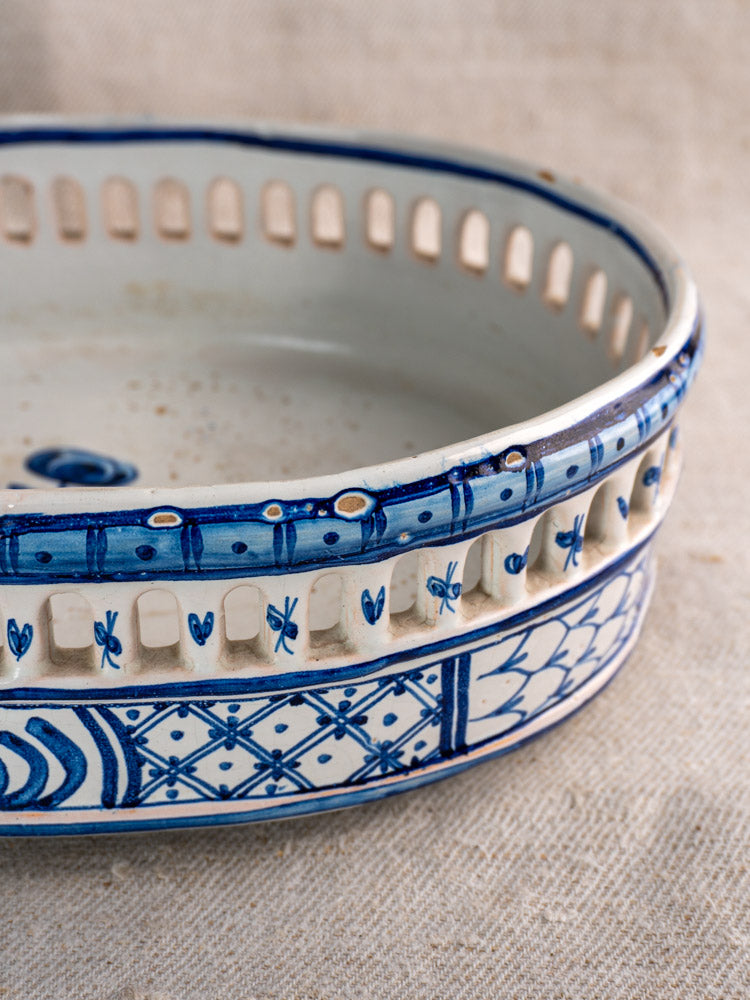 Antique French faience jardinière by Pouplard Béatrix, cobalt blue with white floral motifs, pierced rim, on beige fabric.