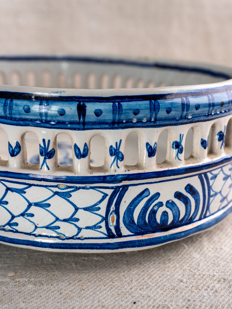 Antique French faience jardinière by Pouplard Béatrix with cobalt blue tin glaze, cut-out rim, on textured neutral surface.