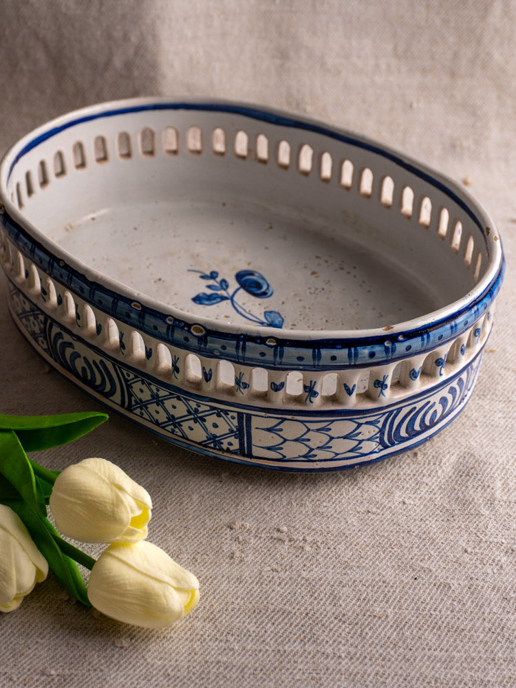 Antique French faience jardinière by Pouplard Béatrix with cobalt blue patterns, displayed beside pale yellow tulips on beige fabric.
