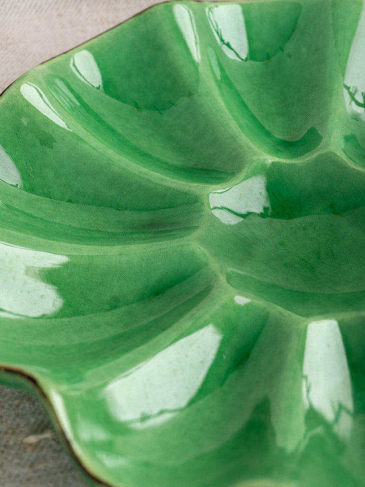 Antique French Dieulefit ceramic melon dish with glossy emerald green glaze, wavy rim, and petal-like leaf motif.