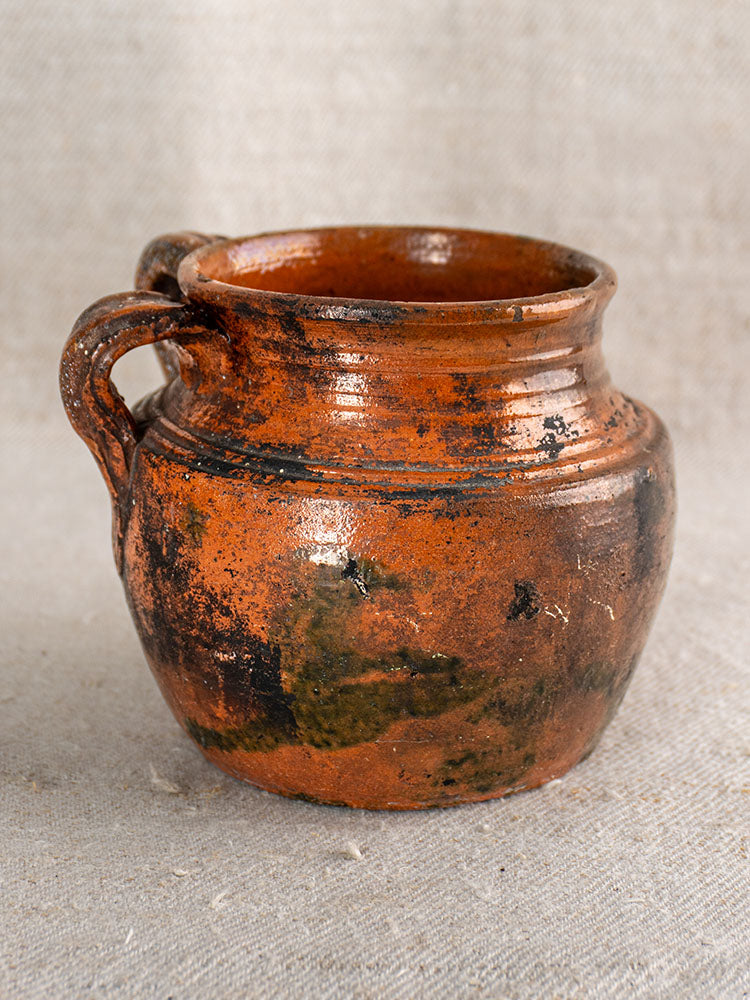 Antique French earthenware rillettes pot with tigré drip glaze, rustic round form, single handle, and textured surface.