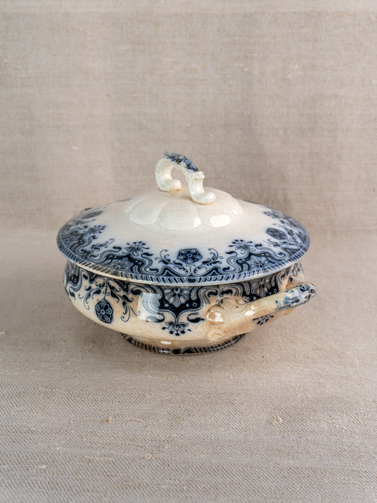 Antique French Badonviller Étoile ceramic tureen with blue floral design and lid on a neutral fabric surface.
