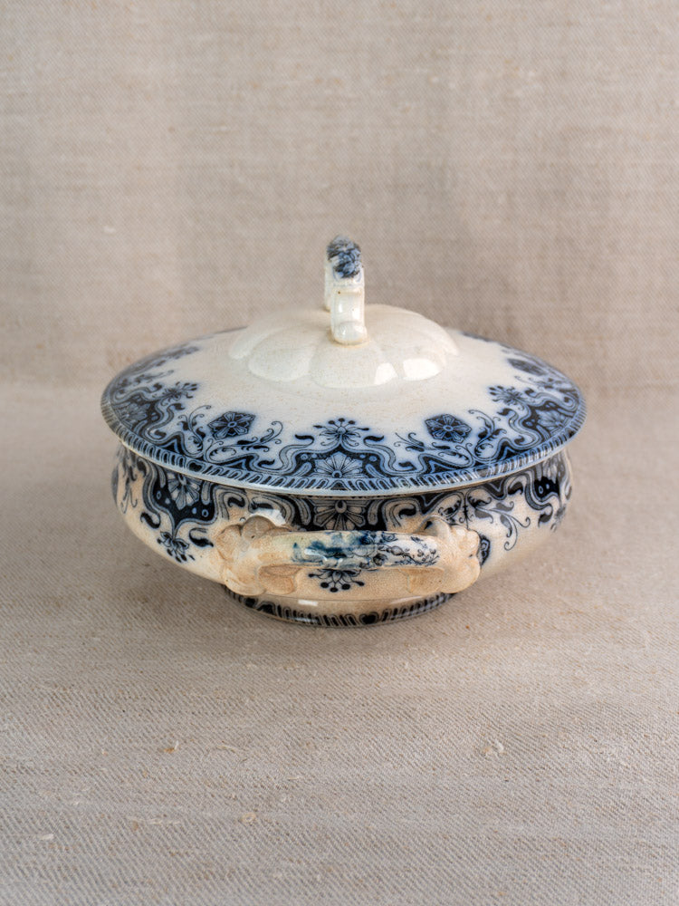 Antique French Badonviller Étoile covered serving dish with blue floral motifs on neutral textured fabric.