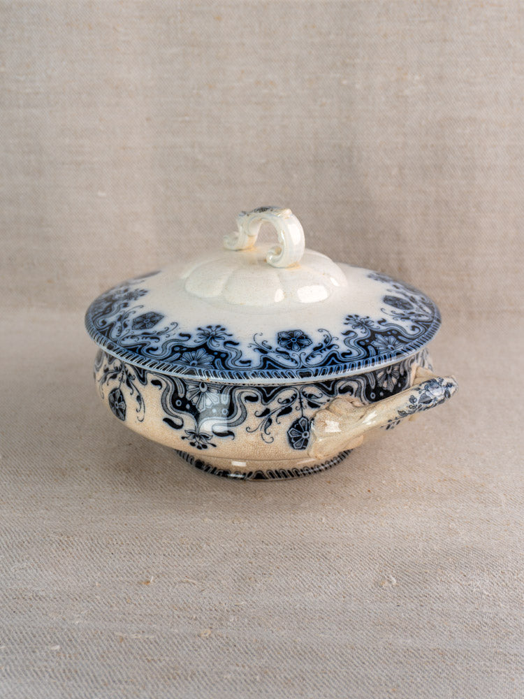 Antique French Badonviller Étoile covered serving dish, circa 1900, blue floral scrolls on cream, on beige textured fabric.