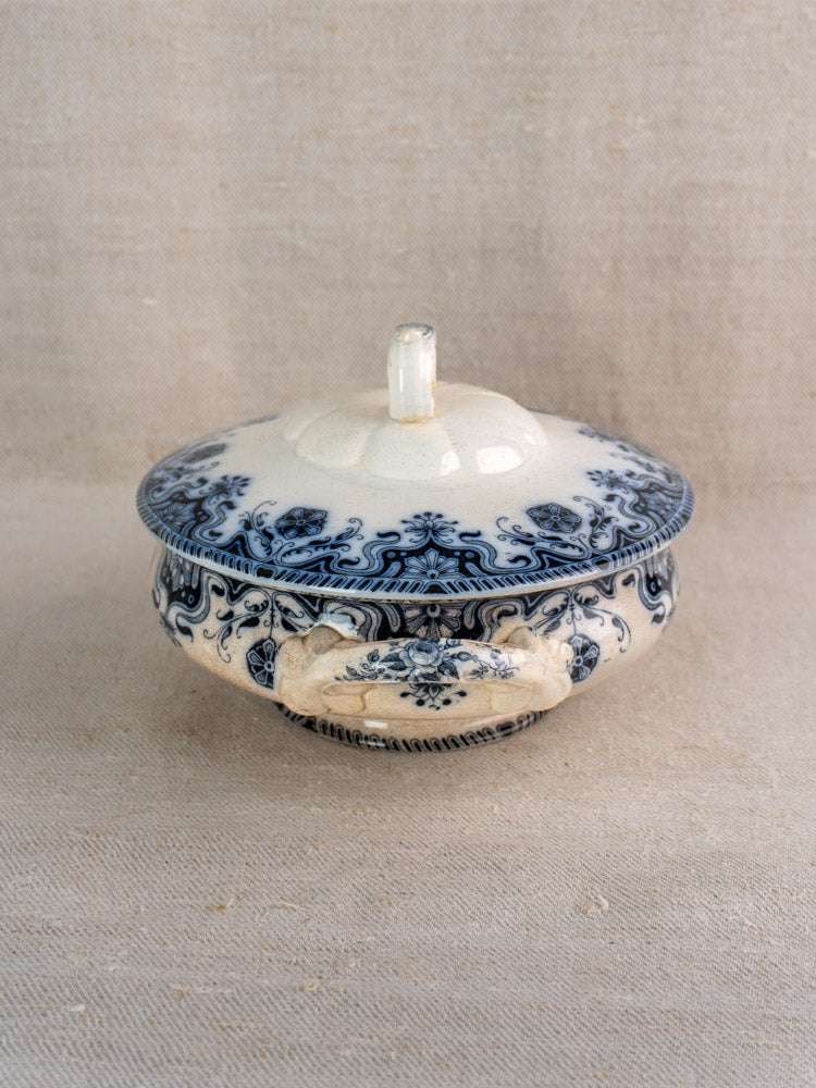 Antique French Badonviller Étoile covered serving dish with blue floral motifs and ornate handles on neutral fabric.