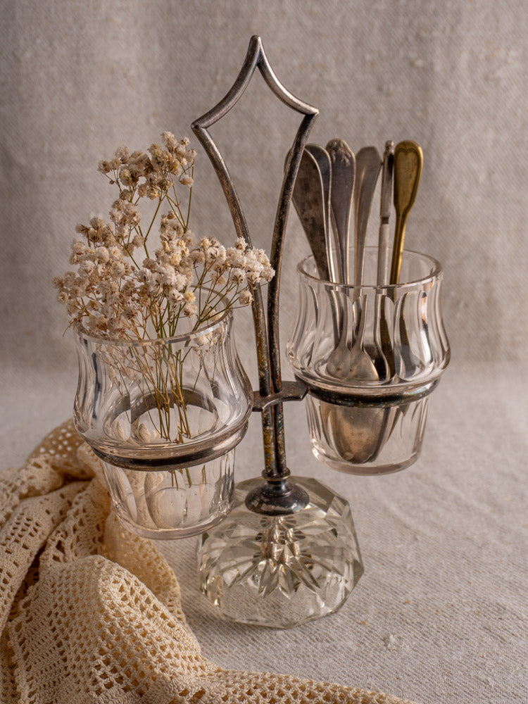 Antique French silver plate and cut glass condiment server with cups, lace base, neutral backdrop.